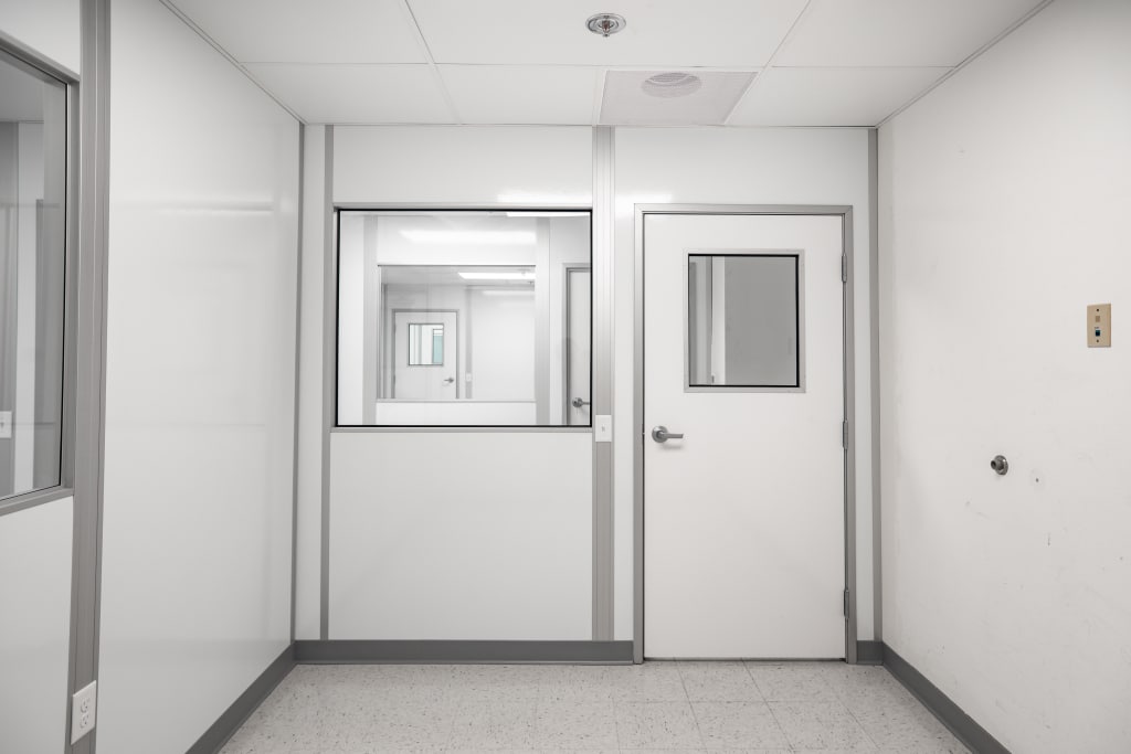 Interior view of a clean, modular room with sealed door and observation window, designed by Allied Cleanrooms.