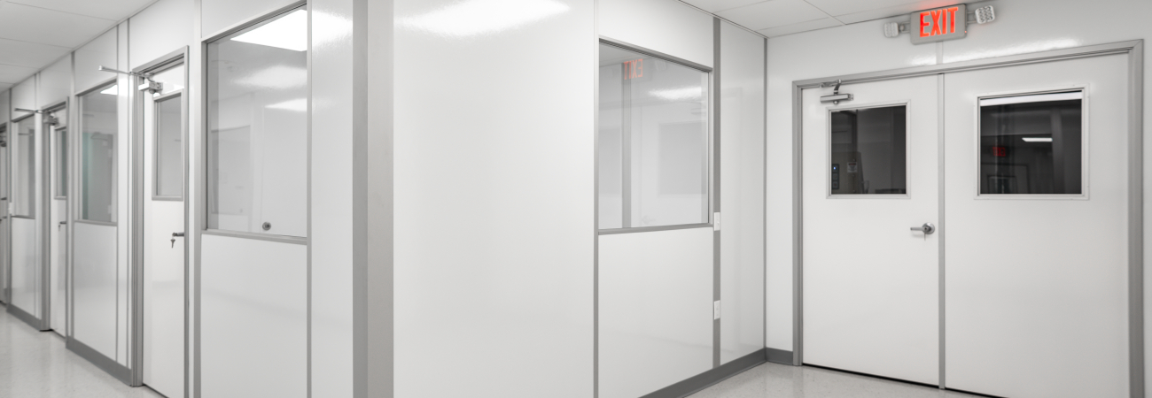 Interior view of a class 100 modular cleanroom corridor built by Allied Cleanrooms, featuring white wall panels and integrated windows.