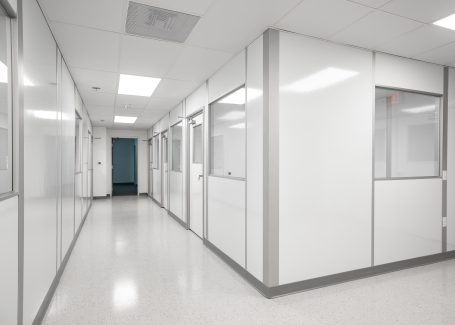 A clean, well-lit modular cleanroom hallway with white panel walls and glass windows, designed by Allied Cleanrooms.