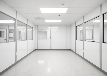Modular cleanroom by Allied Cleanrooms featuring white panel walls, large interior windows, a polished seamless floor, and a grid ceiling with integrated lighting—designed for controlled environments in pharmaceutical or laboratory settings.