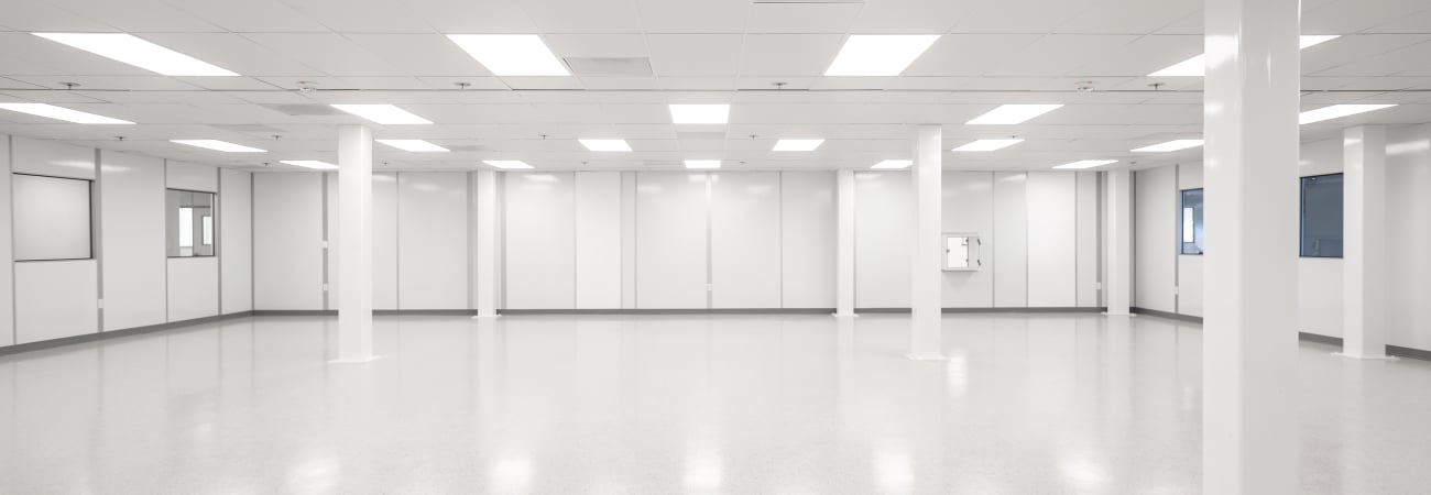 A spacious, brightly lit cleanroom featuring smooth, seamless cleanroom flooring and white walls.