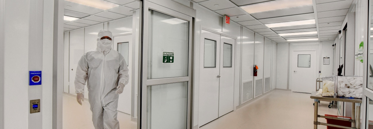 Person in full cleanroom gown exiting modular class 100 cleanrooms built by Allied Cleanrooms.
