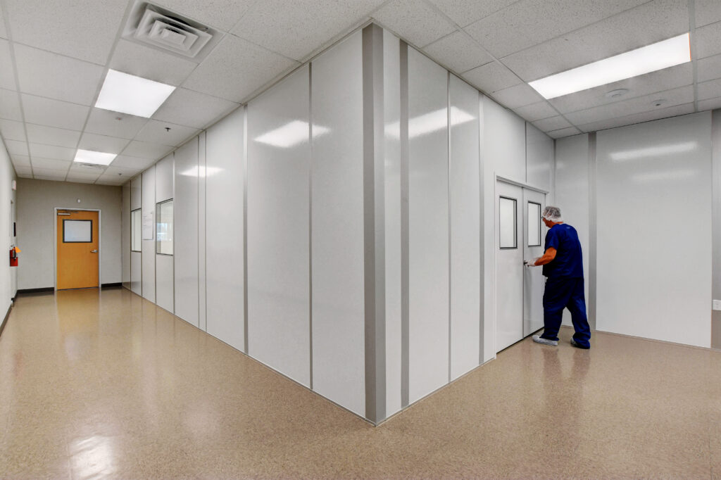 A man enters a door in a cleanroom environment.