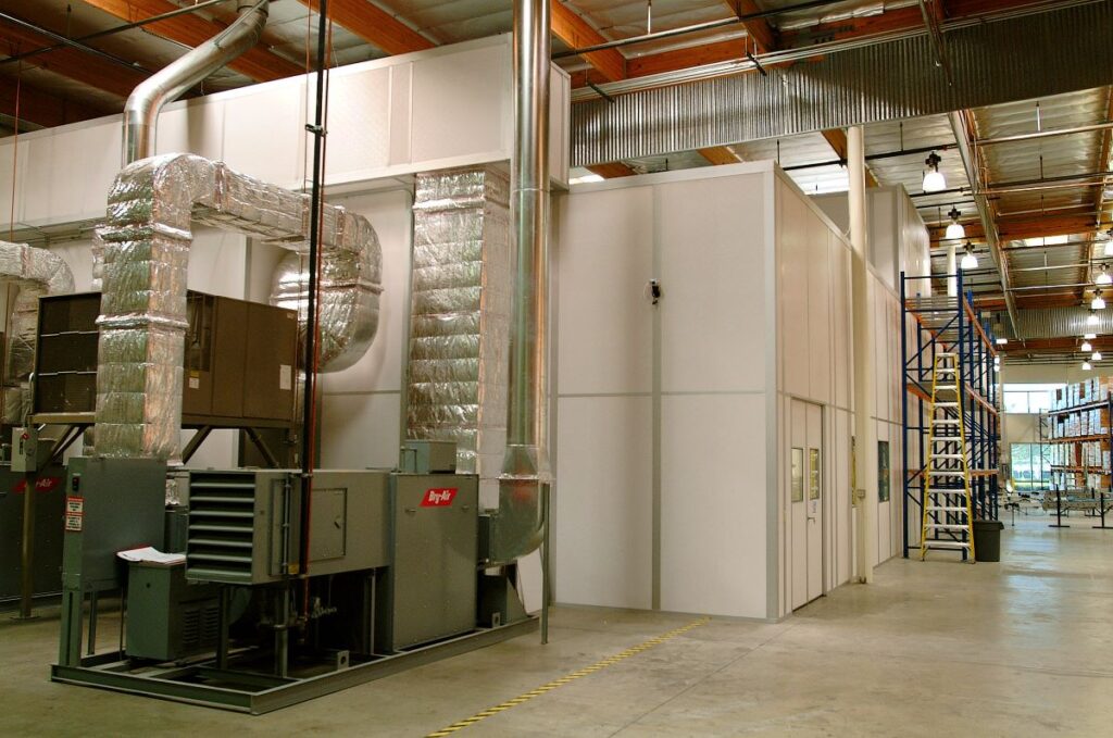 An industrial cleanroom with air handling units, insulated ductwork, and modular walls.
