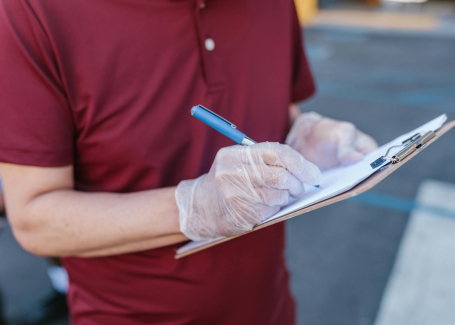 Person wearing gloves writes on a clipboard during a cleanroom testing inspection for GMP compliance for cleanrooms (at Allied Cleanrooms).