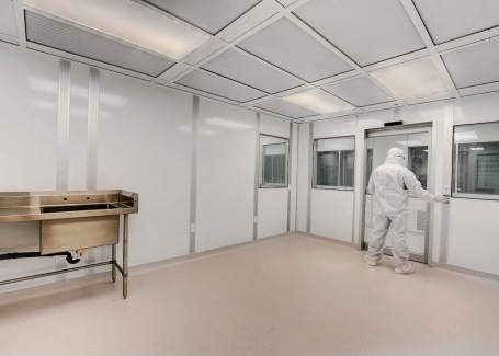 A man in gowning works in an ISO 4 cleanroom by Allied Modular.