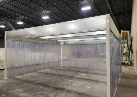 Softwall cleanroom with clear flexible walls and a sturdy overhead frame inside an industrial facility.