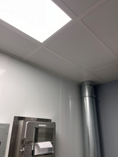 Modular Laboratories: Definition, Benefits, and Features A cleanroom ceiling with bright lighting, a stainless steel pass-through chamber, and an air duct system.