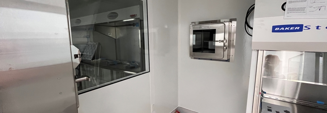 Interior of a modular cleanroom by Allied Cleanrooms, featuring a pass-through chamber, observation window, and work station.