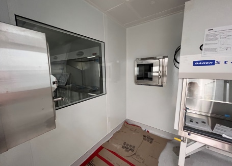 Interior of a modular cleanroom by Allied Cleanrooms, featuring a pass-through chamber, observation window, and work station.