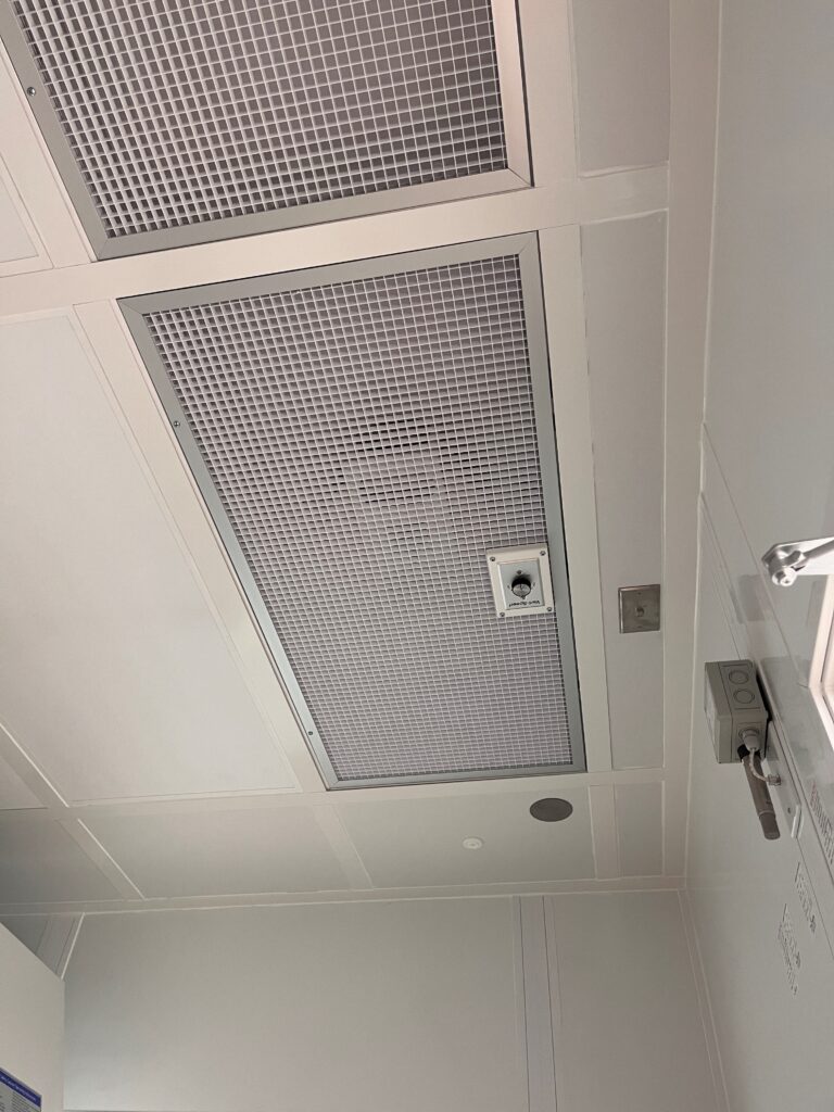Cleanroom ceiling featuring gridded panels with HEPA filters integrated into a Fan Filter Unit (FFU) system.