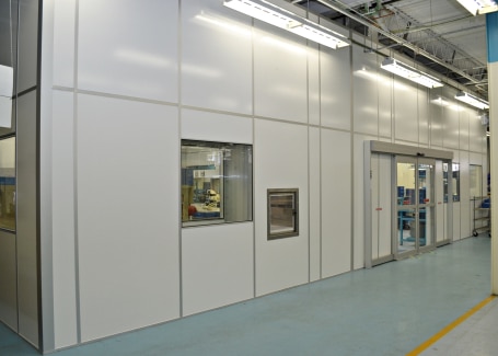 Modular cleanroom with wall panels, viewing window, pass-through chamber, and sliding door, built by Allied Cleanrooms.