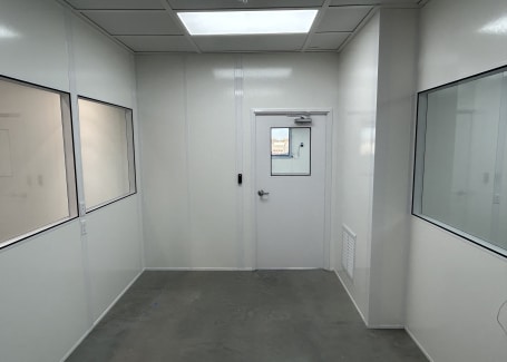 Interior of temperature-controlled rooms by Allied Cleanrooms, showing modular insulated walls, a sealed door, and cleanroom windows.