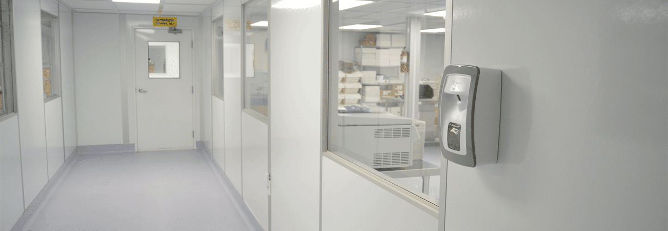 Interior hallway of a modular cleanroom built by Allied Cleanrooms, featuring flush wall panels, interior windows, and a wall-mounted sanitizer dispenser.