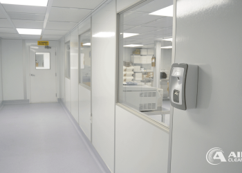 Interior hallway of a modular cleanroom built by Allied Cleanrooms, featuring flush wall panels, interior windows, and a wall-mounted sanitizer dispenser.