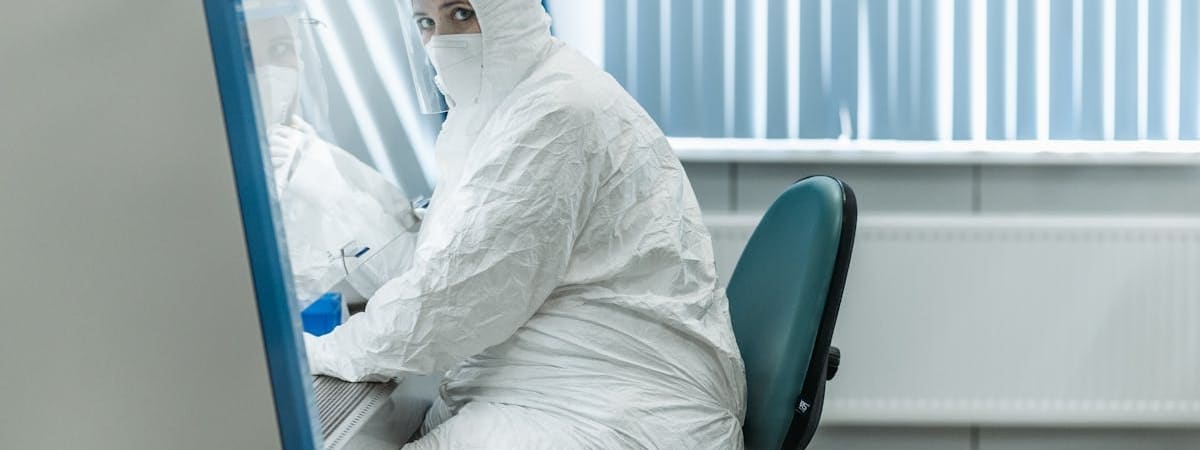 Technician in full cleanroom gowning seated at workstation inside an Allied Cleanrooms modular cleanroom