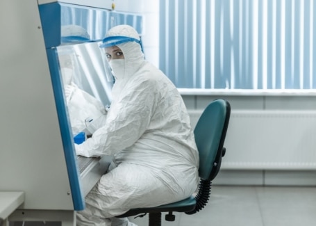 Technician in full cleanroom gowning seated at workstation inside an Allied Cleanrooms modular cleanroom