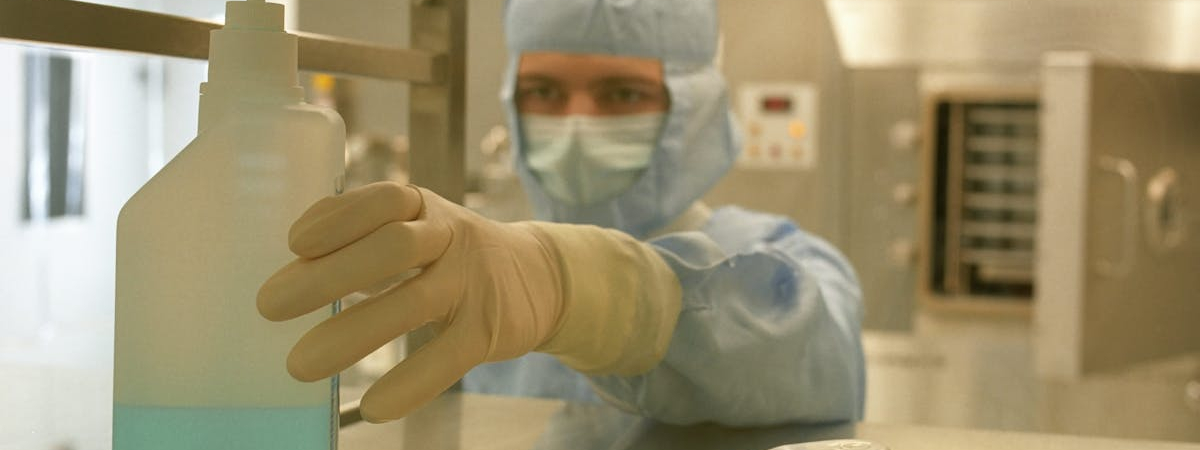 Cleanroom technician following cleanroom gowning procedures with gloves, mask, and full protective suit in a controlled environment by Allied Cleanrooms